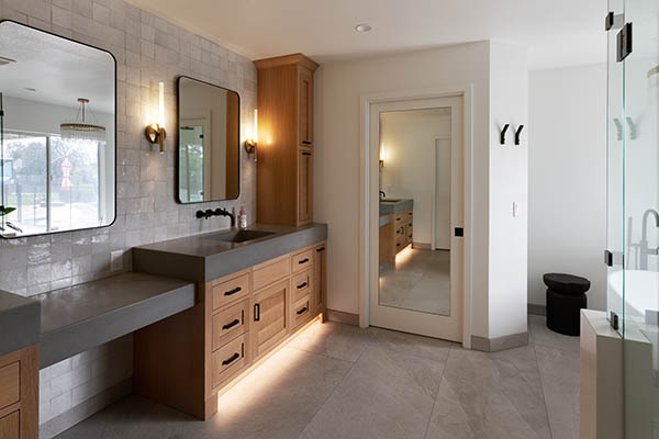 remodeled white bathroom with wooden cabinets and and granite sinks