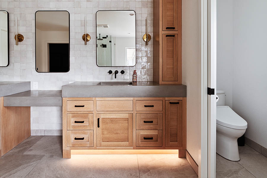 mirrors on tile backsplash and wooden cabinets with granite sinks