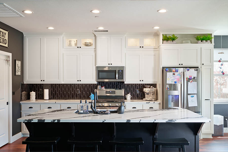 white kitchen with black island that has a marble top